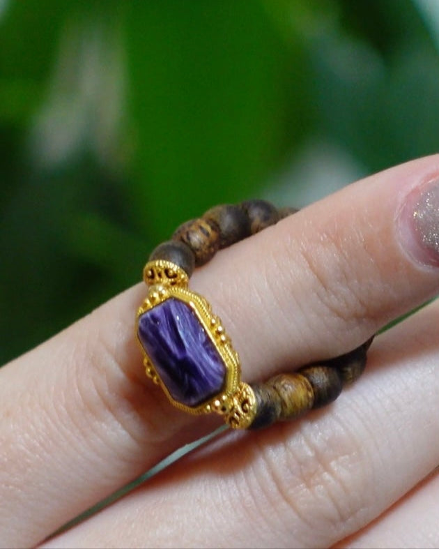 Close-up of purple charoite gemstone in gold vermeil and agarwood band, symbol of spiritual clarity