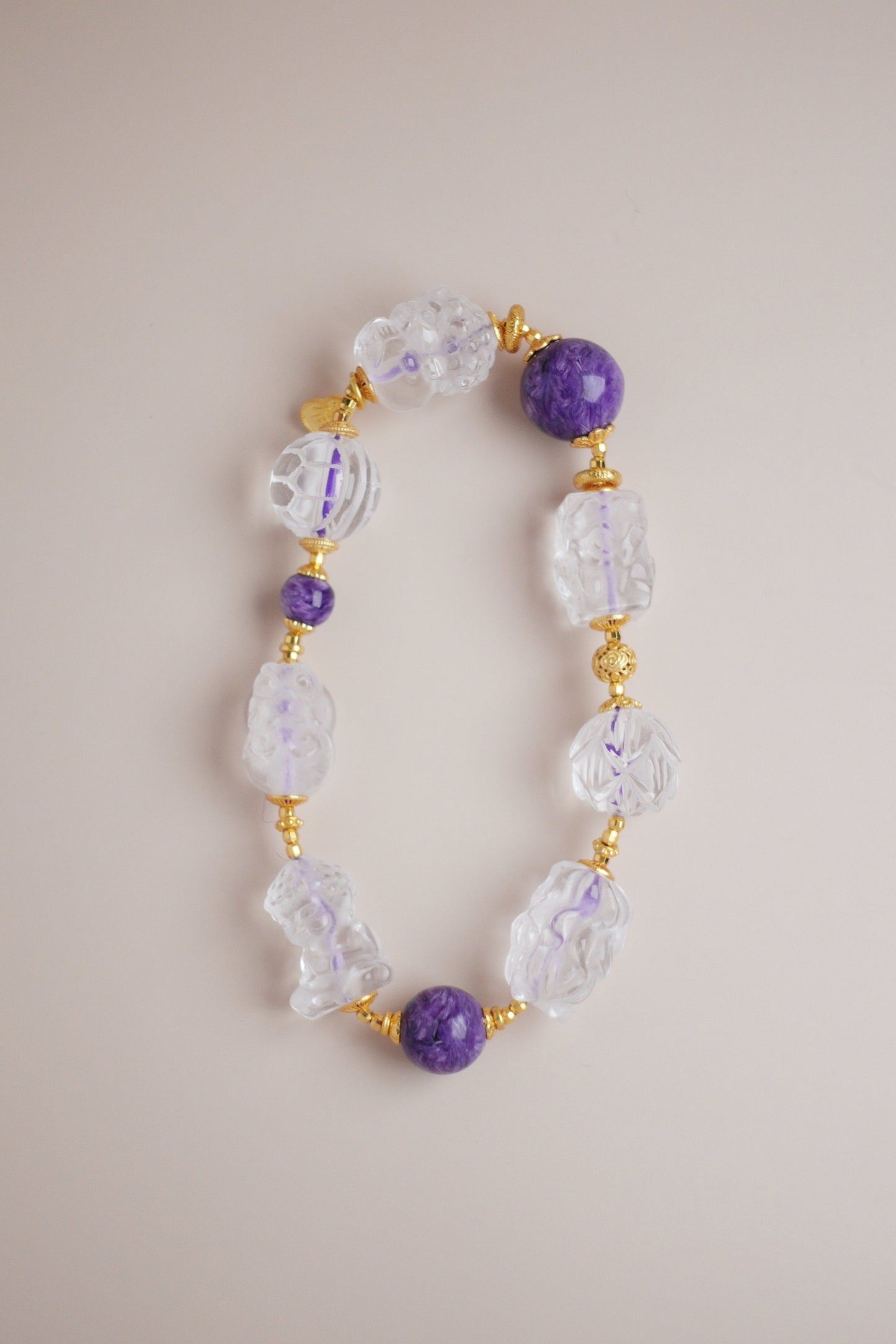 Eight‑Blessings charm bracelet with purple charoite beads and carved white quartz charms of turtle, Pixiu, Buddha, lotus, koi & fox.