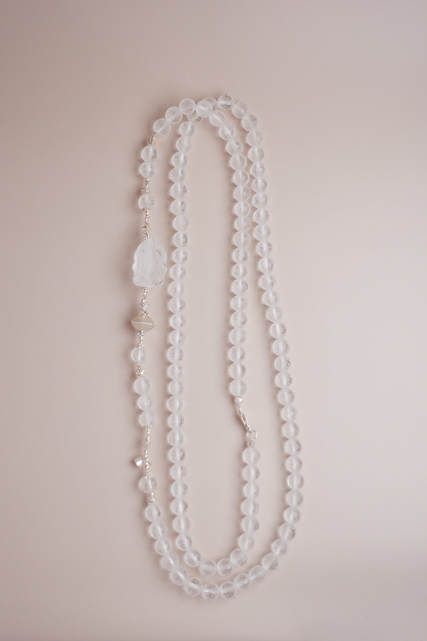Frosted clear quartz mala necklace with Om Mani Padme Hum engraving and carved Baby Ganesha charm on silver accents.
