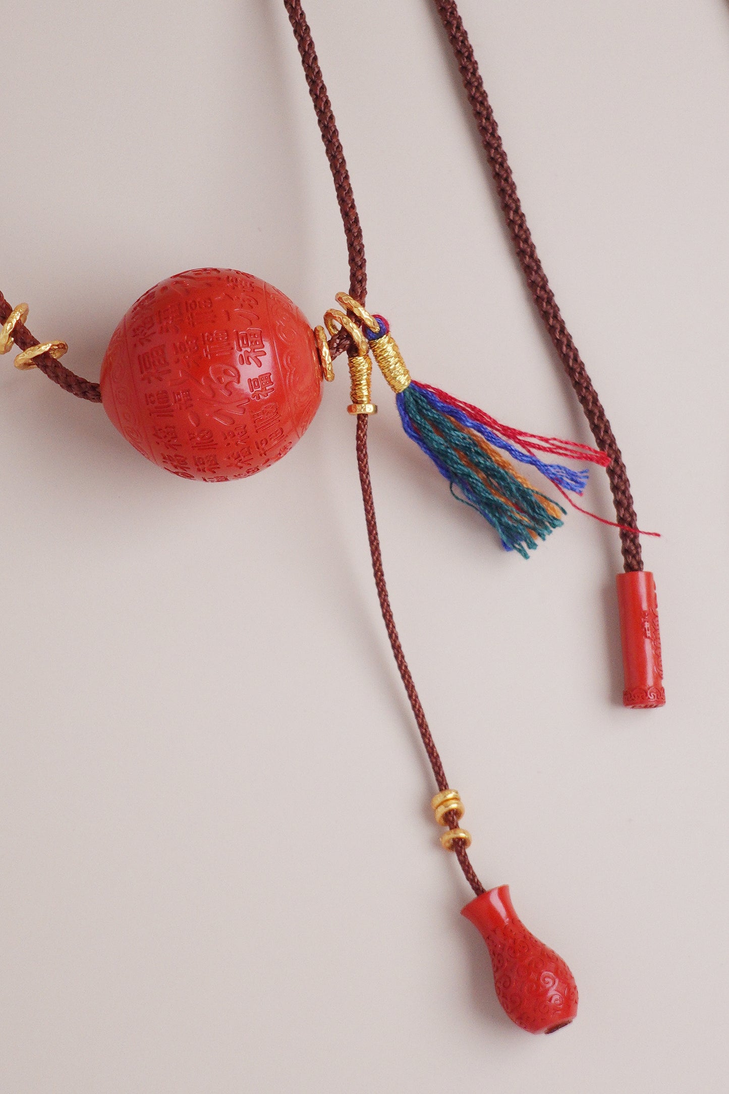 Full-Blessing cinnabar vase pendant necklace on brown cotton–linen cord with multicolor tassel and 24k gold vermeil silver accents.