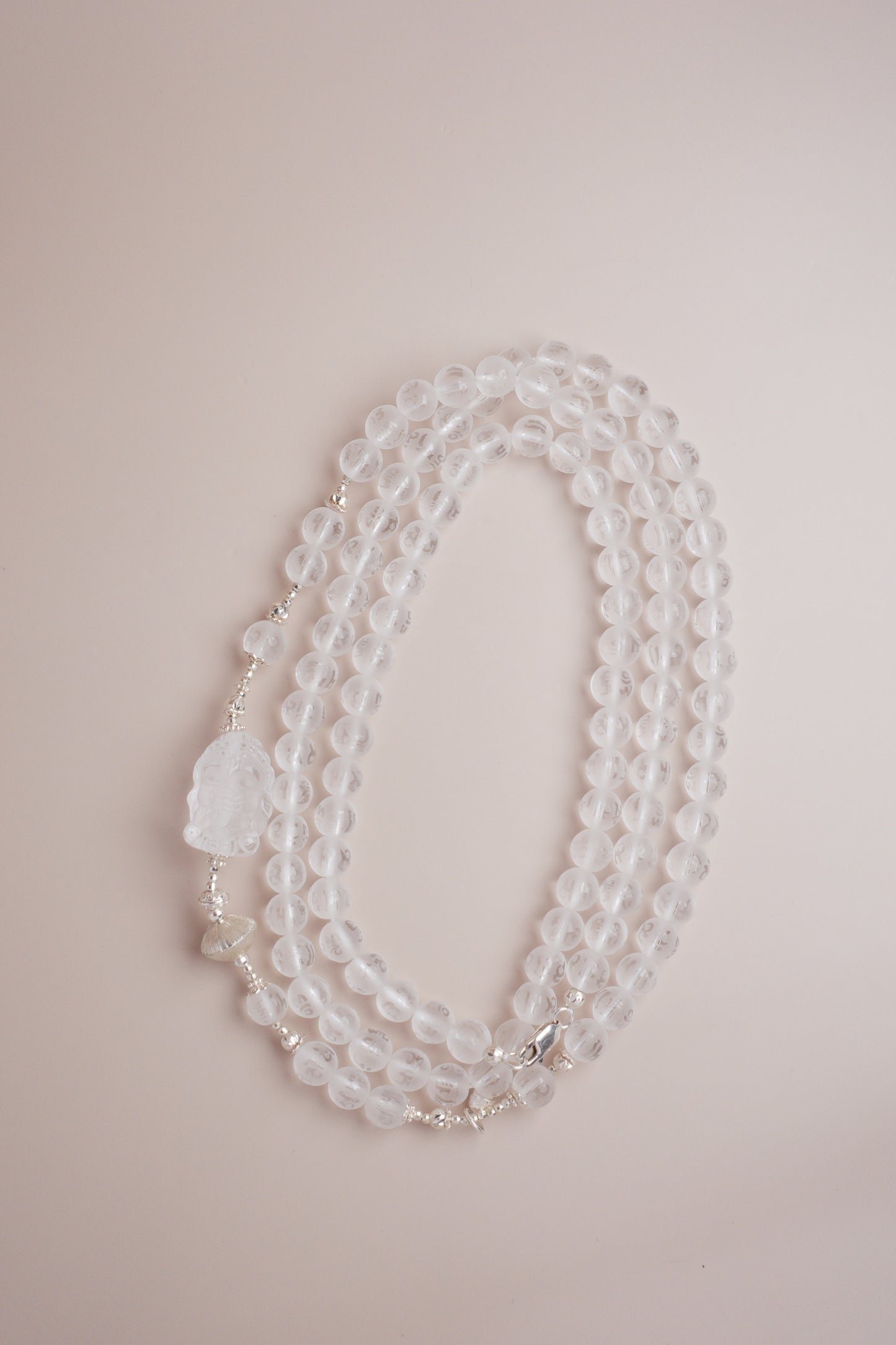 Quartz necklace featuring Om Mani Padme Hum mantra engraving and a frosted Baby Ganesha carving.