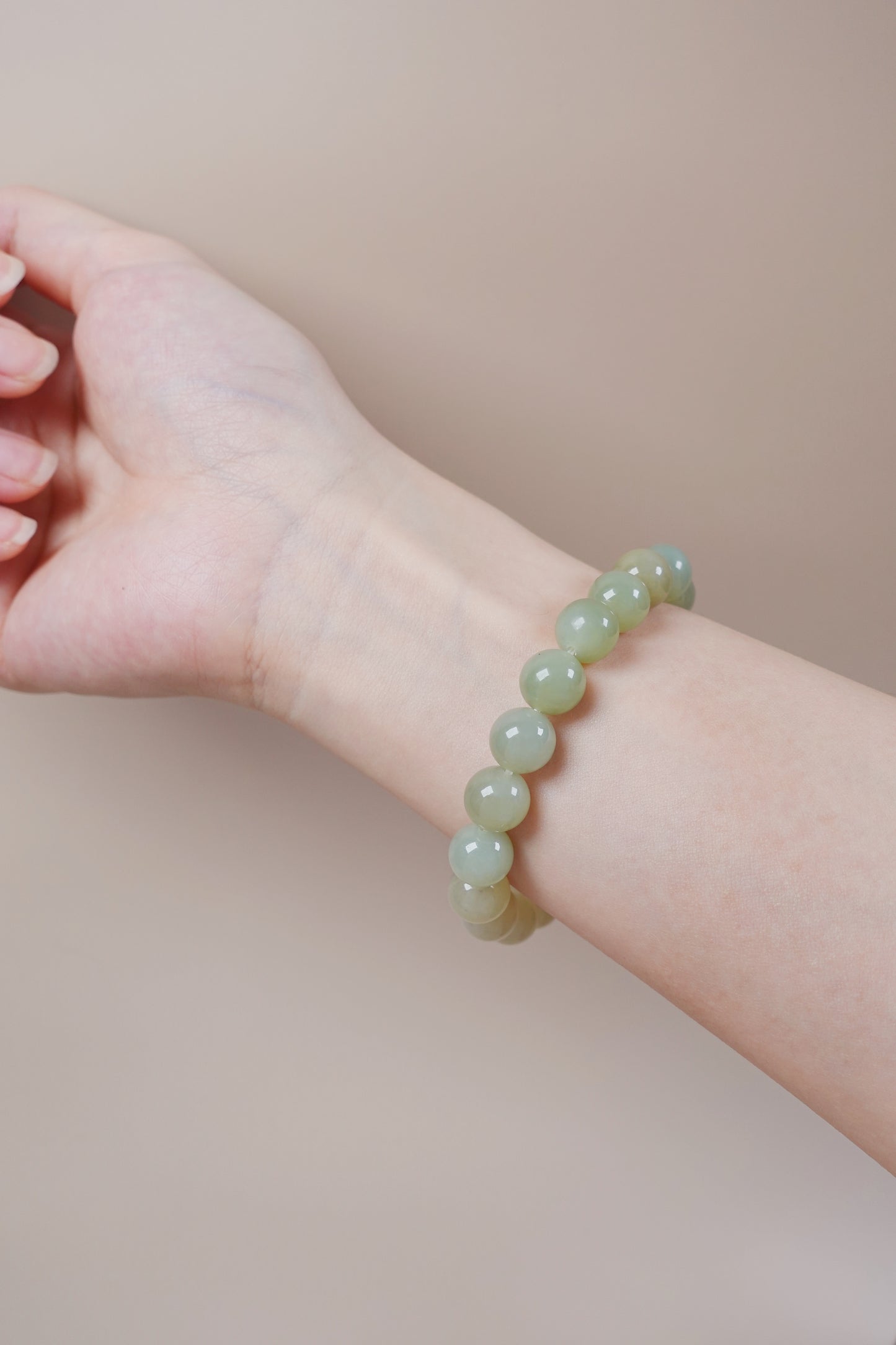 Close-up of 10mm pale green jade beads in natural gradient, symbol of emotional clarity and growth