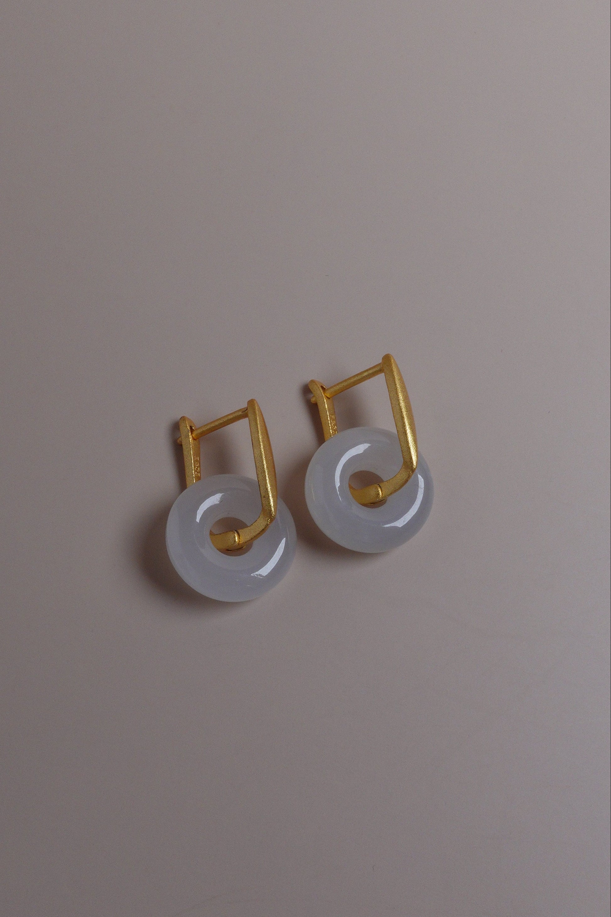 Pair of earrings with white stones and gold accents on a beige background