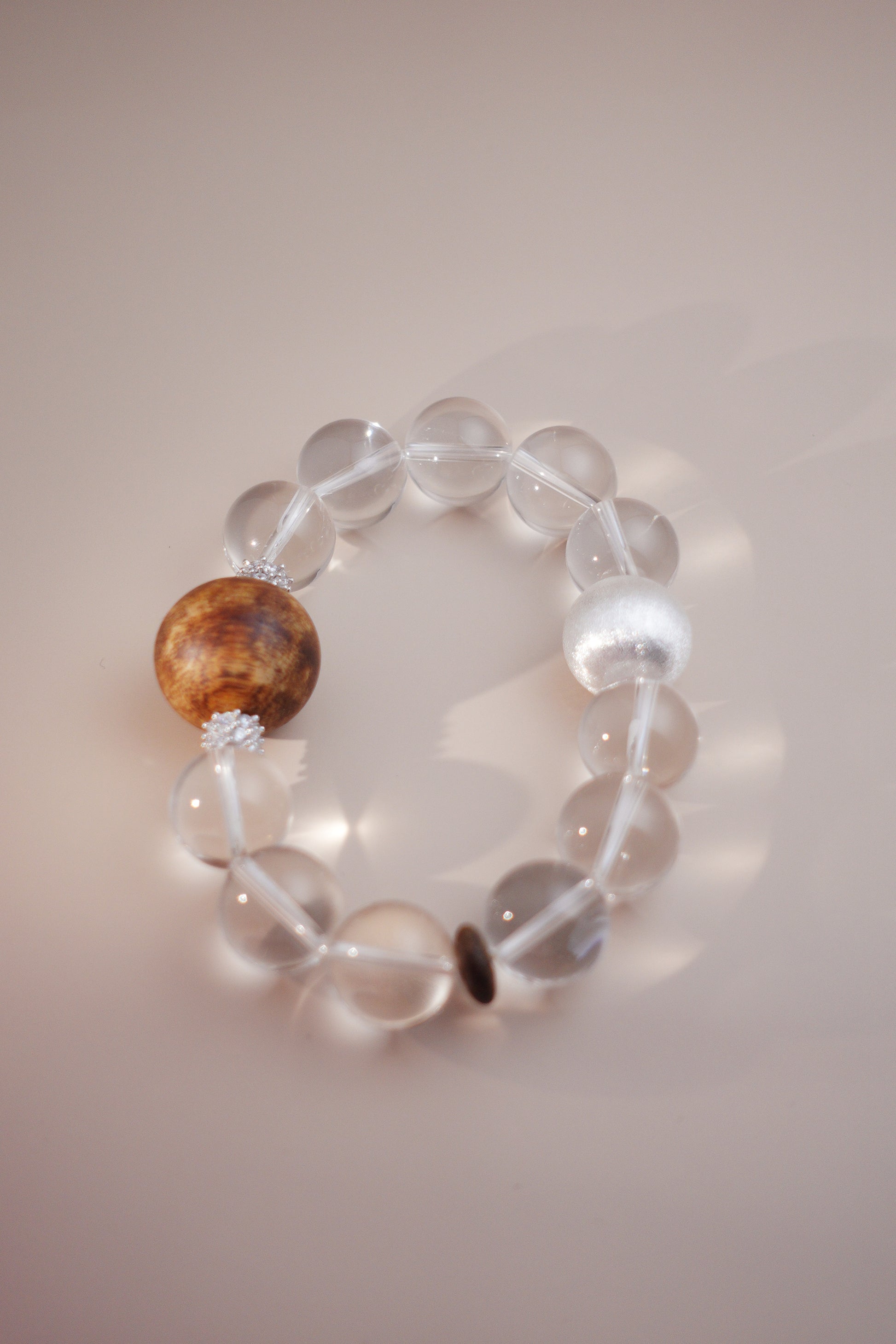 Tranquil Essence bracelet with 15 mm clear quartz beads and a 20 mm Hainan Chenxiang focal bead on stretch cord.