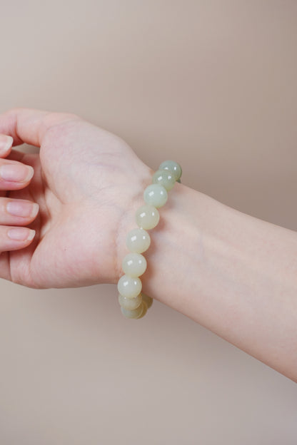 10mm pale green Hetian jade gradient bracelet, symbolic Wood element jewelry.Hetian jade bracelet in soft green gradient worn on wrist, Heart Chakra balance and grounding