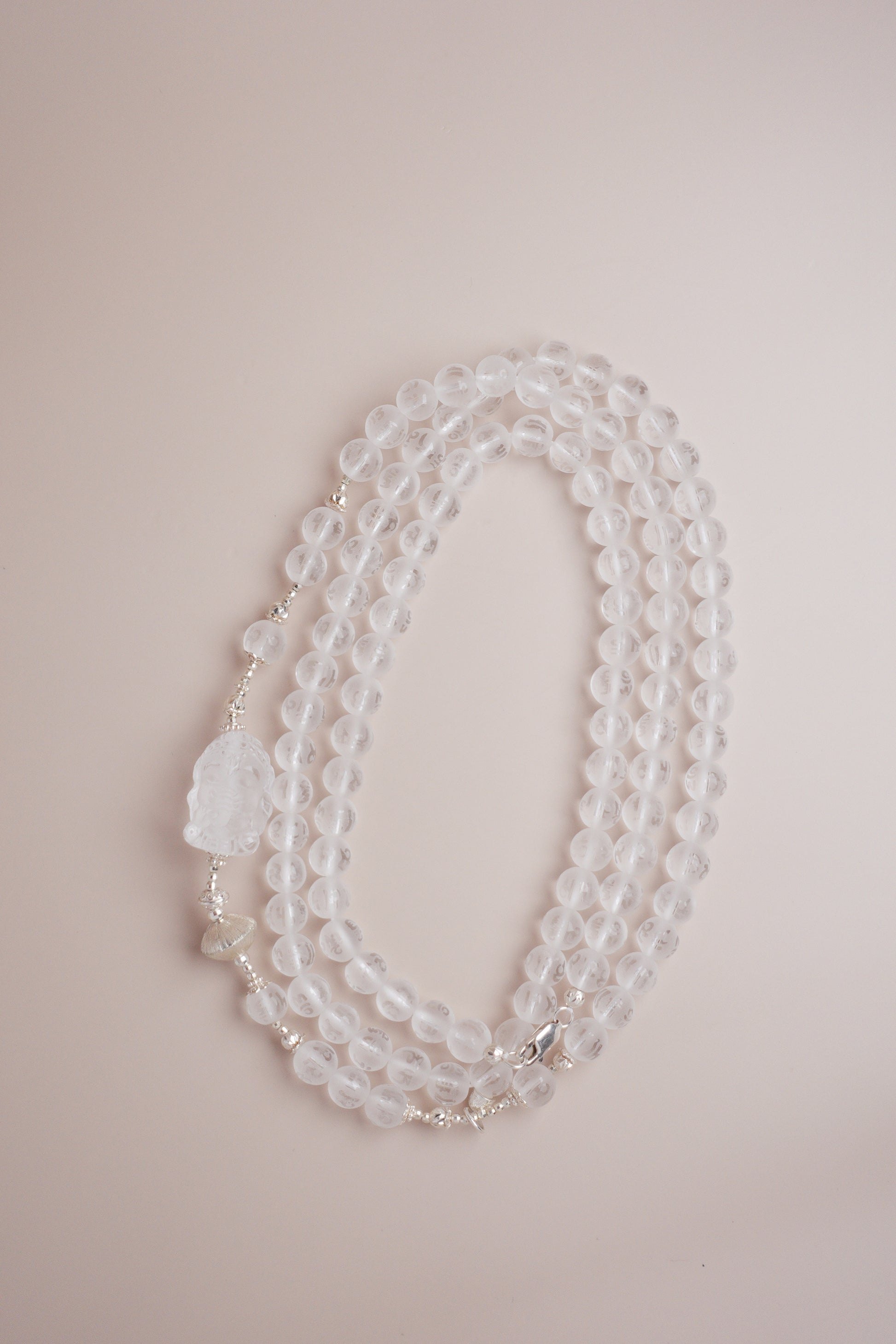 Quartz necklace featuring Om Mani Padme Hum mantra engraving and a frosted Baby Ganesha carving.