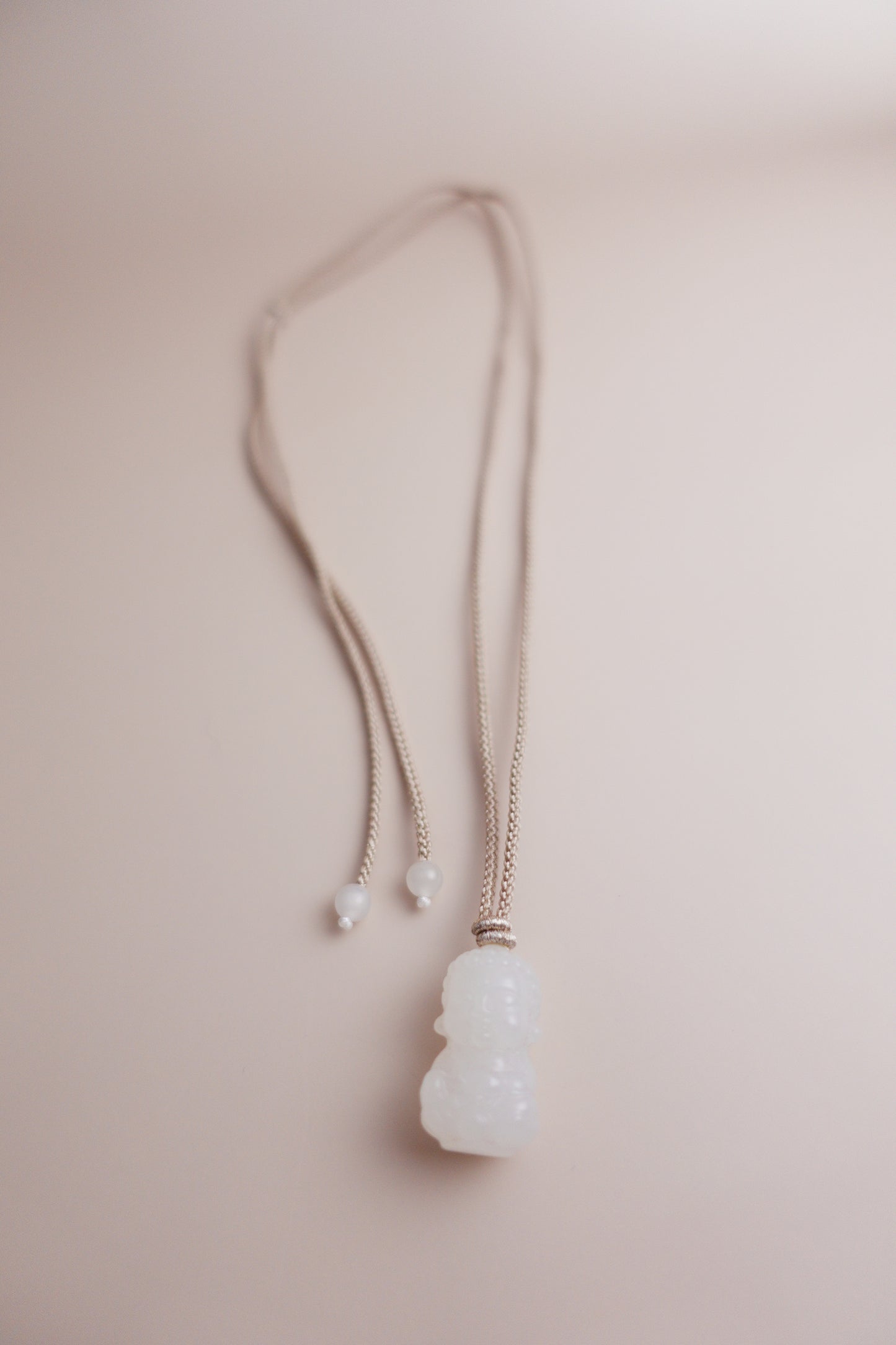 Adjustable hand-braided cord necklace with a hand-carved Hetian white jade Baby Buddha pendant.