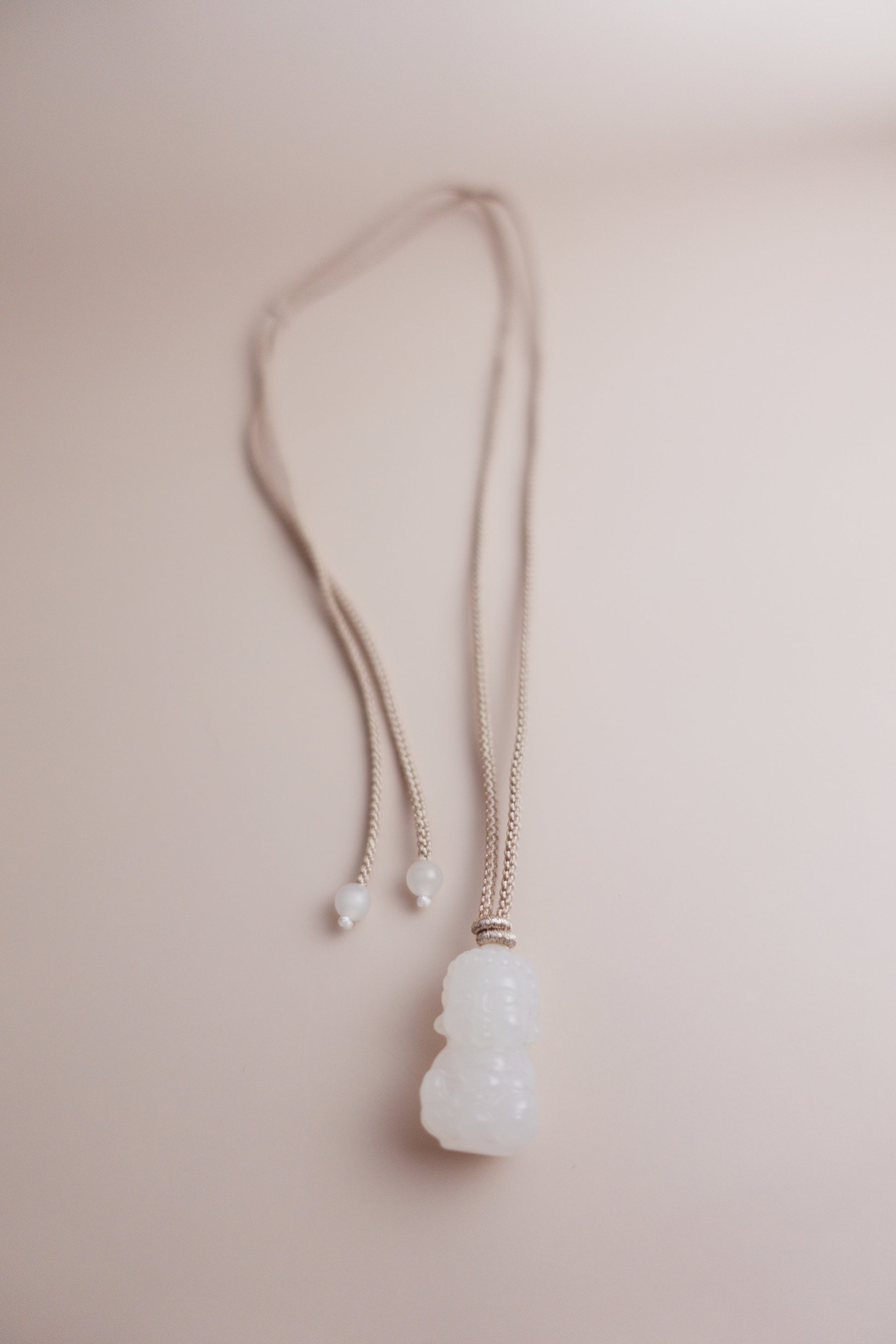 Adjustable hand-braided cord necklace with a hand-carved Hetian white jade Baby Buddha pendant.